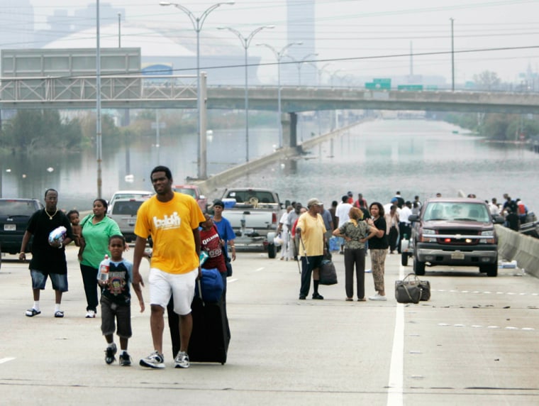 Rescued residents walk from floodwaters in front of Superdome in New Orleans